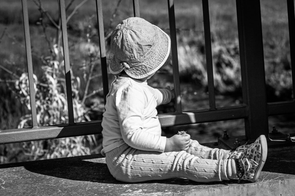 Bedingungslose Liebe – Ein Moment mit meinem Kind Kleines Kind sitzt an einem Geländer und blickt ins Freie – Symbol für bedingungslose Liebe und tiefe Verbindung