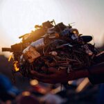 Hände halten einen schweren Stapel unscharfer Gegenstände – Symbol für die Last des Besitzes.