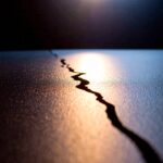 Eine glatte Fläche mit einem feinen Riss – Symbol für Bruch der Gewohnheit und Selbstreflexion.